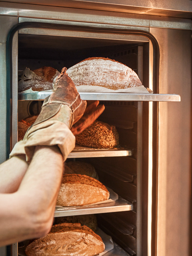 Glutenfreies Brot wird in Backofen geschoben 